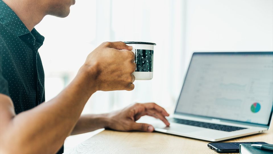 man reading laptop with coffee